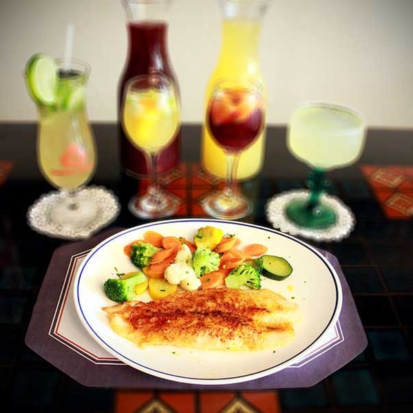 Cuban Cafe's seasoned fish fillet with steamed vegetables and various colorful drinks.